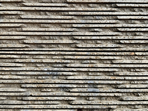 Close up of stacked andesite stone wall texture, with 3D rough horizontal strips fluted pattern. Suitable for wall cladding, flooring, and tiles. For interior and exterior walls. Seamless background t