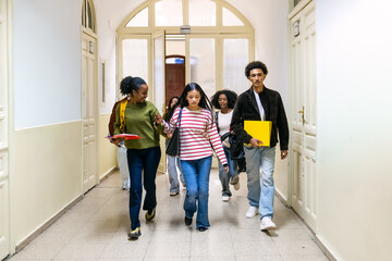 Obraz premium Diverse group of high school or college students walking and communicating in an educational building corridor