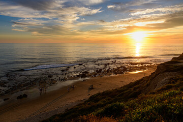 Obraz premium Gentle waves rolling onto the shore at Crystal Cove during dusk 