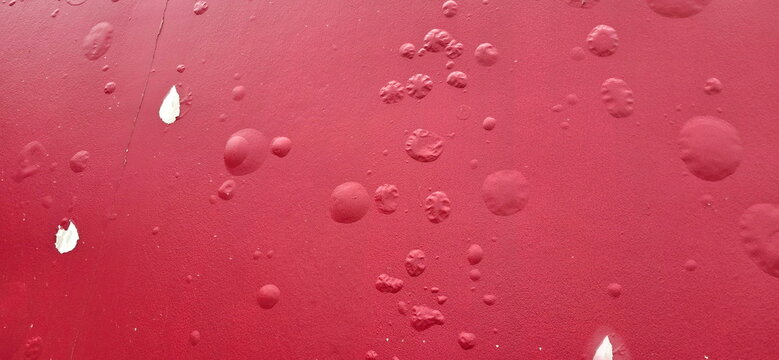 The background of red painted wall has blistered paint marks and some parts were peeling, revealing original white wall. The red painted cement wall has blistered paint marks. Blistered colored film 
