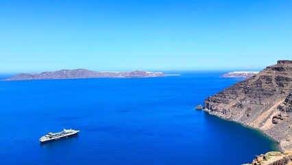 Obraz premium Cruise liner sailing within Santorini caldera, Greece against sweeping Aegean horizon, capturing iconic island setting and luxury travel experience