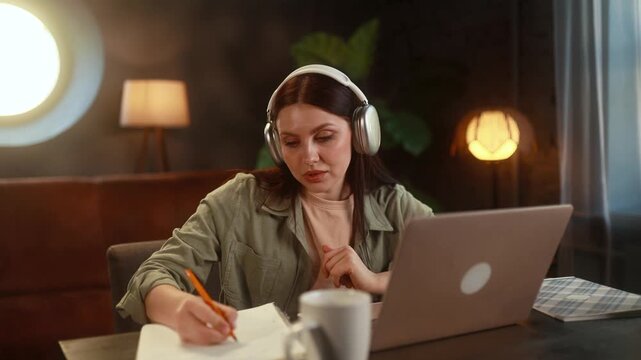 Young woman fully concentrated on her online studies at home, carefully following the lesson on her laptop and actively engaged in distance education in a quiet, comfortable indoor setting