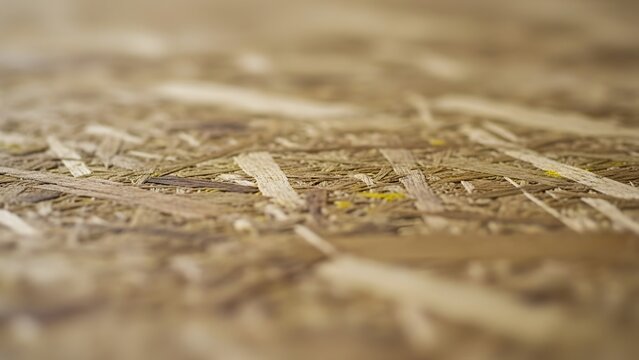 Abstract and detailed close-up of an oriented strand board (OSB) surface, highlighting the unique raw wood texture with shallow depth of field, ideal for industrial or natural design backgrounds