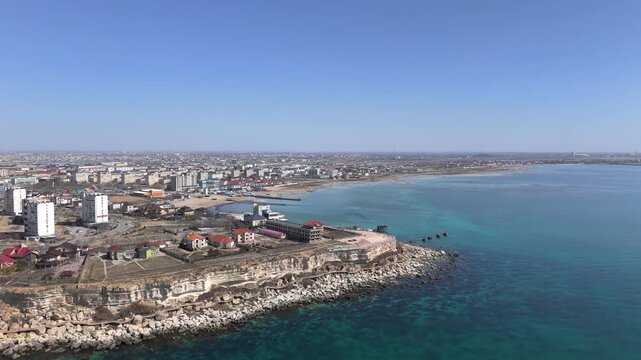 Stunning top-down drone shot of Aktau city houses perched on a dramatic rocky cape. This footage showcases the unique Mangystau landscape where urban living meets the rugged Caspian Sea coastline. 