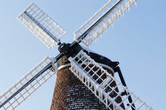 A windmill with its blades frozen solid and heavily coated in thick rime ice and snow.