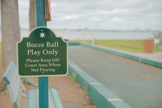 Green bocce ball sign marks a dedicated outdoor court by the waterfront in Gulfport, Florida with benches and a relaxed park setting for casual play, leisure, and community recreation.
