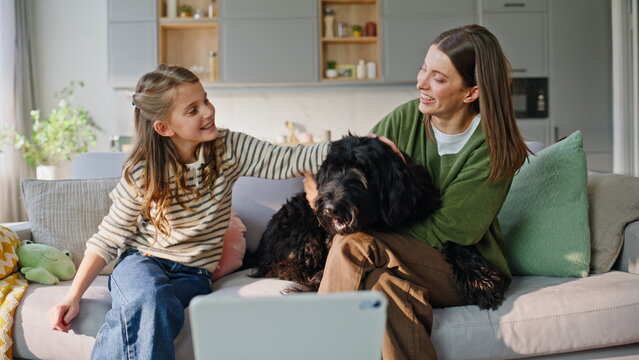 Overjoyed relatives petting dog sofa closeup. Adult young sisters caressing pet