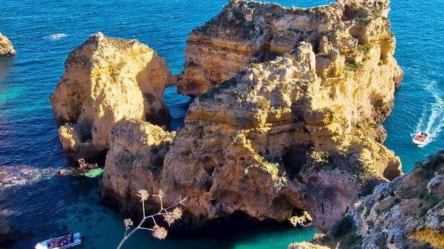 Portugal Algarve Praia da Marinha aerial view, yellow rock arch with boats in turquoise sea, 4K cinematic coastal scenery golden cliffs