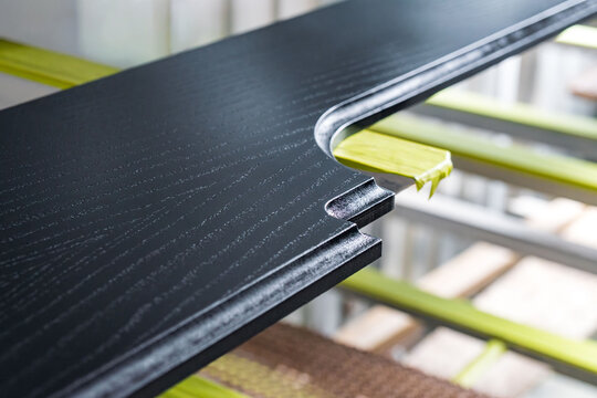 Wooden furniture element is placed in a drying chamber. The piece is made of oak veneer and is coated with black enamel for finishing. It is part of a wood treatment process