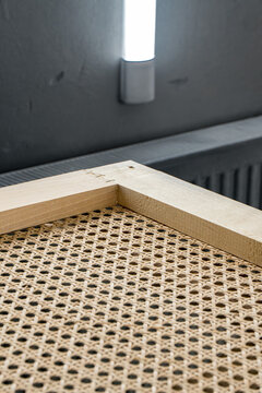 Handcrafted wooden frame with natural rattan webbing inside a professional paint booth, showcasing high-quality furniture craftsmanship and finishing