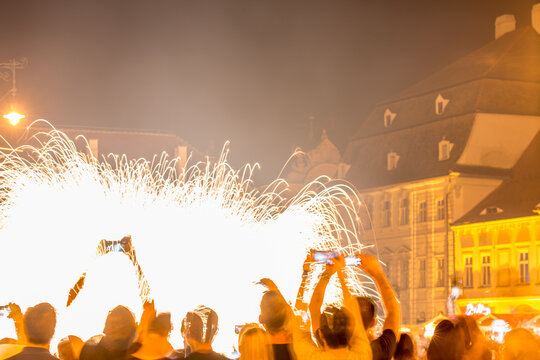 Long exposure motion blurred photograph. SIBIU, ROMANIA: People are watching a firework display in a city square