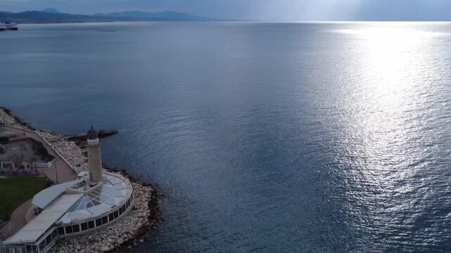 Aerial dynamic view of a traditional lighthouse on a pier by the ocean
