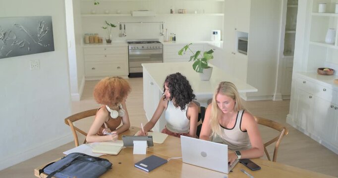 Diverse women at table kitchen center pointing tablet urging left taking notes right typing laptop