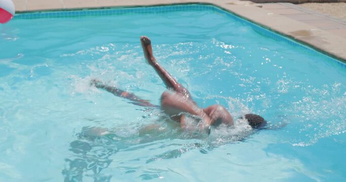 African man shirtless and boy in pool climbing on back, playing, grappling, tumbling, surfacing