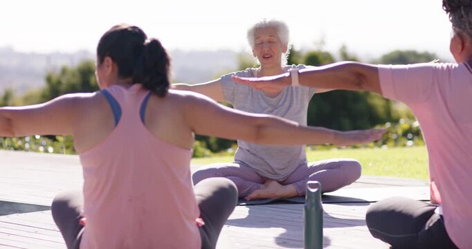 Senior African American coach opening arms guiding women doing arm extensions to align on deck mats