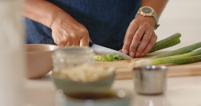 Senior African woman placing scallion and chef knife, rocking, slicing in kitchen on board for meal