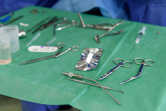 Surgical instruments for ENT surgery on a green sterile field in the operating room, closeup of otolaryngology medical tools, scissors, clamps, and speculum prepared for a procedure