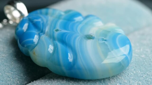 A blue agate gemstone pendant with a wavy striped design