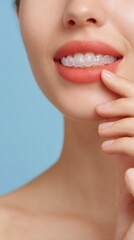Obraz premium Close Up Of Woman Smiling With Clear Aligners And Sparkly Lips Against Blue Background