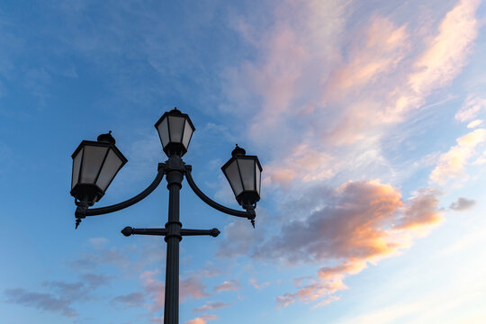 Vintage street lamp against dramatic sunset sky in old town