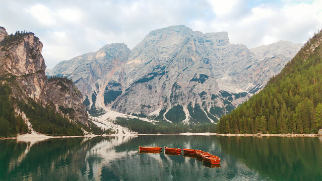 Lake braies with wooden boats reflecting dolomites mountains