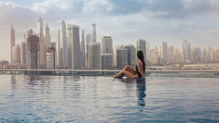 Woman relaxing in infinity pool overlooking dubai cityscape © Chris M