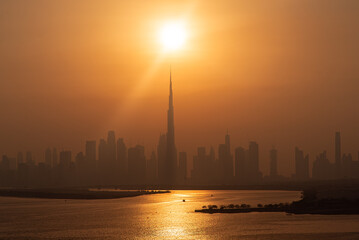 Obraz premium Burj khalifa tower reaching sun during dubai sunset