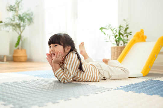 Girl Plays on the Floor in a Bright Playroom With a Slide and Soft Mats During the Day