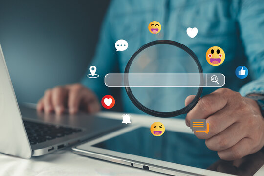 Businessman holding magnifying glass over AI search bar with social media emoji icons. Concept of digital marketing, social listening, consumer behavior analysis, and AI search engine optimization.