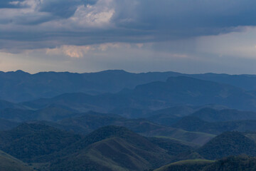 Fototapeta premium Layered Mountain Landscape Under Dramatic Storm Clouds and Rain