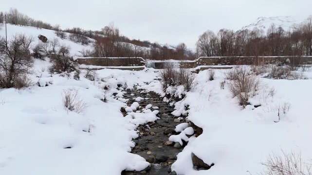 Snow blankets quiet winter forest with rocky stream