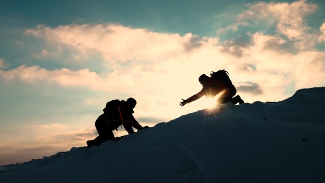 Teamwork business people. Go towards your goal. Travelers climb one after another on rock. Climbers silhouettes stretch their hands to each other climbing to top of hill. Team of businessmen victory