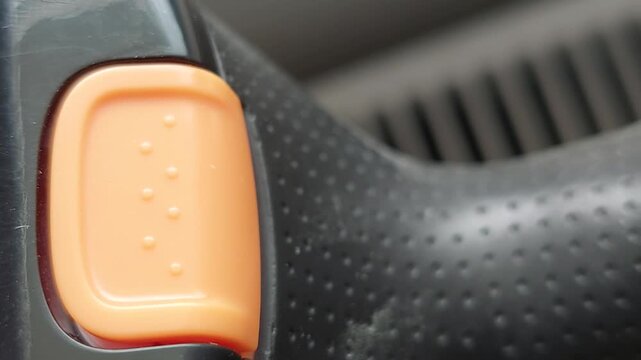 Macro shot of finger pressing orange button with braille dots