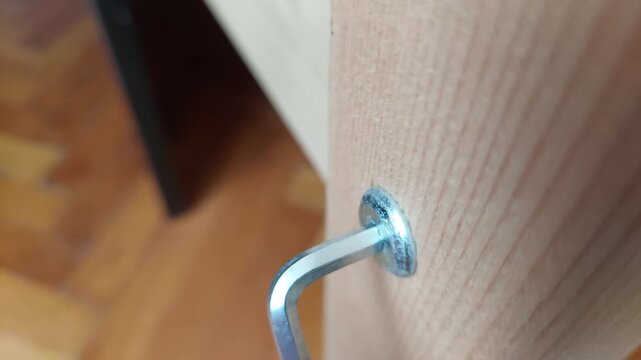 Tightening a screw in a wooden furniture leg with an Allen key close up