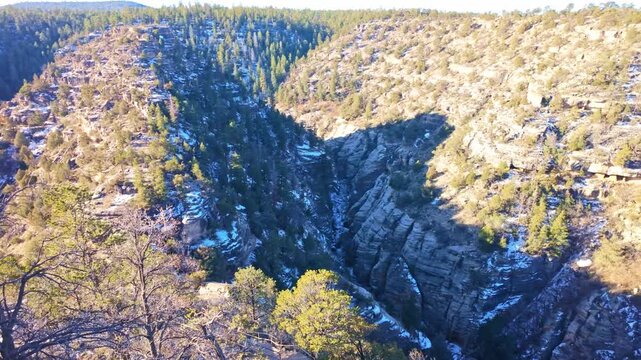 Aerial panorama shows Walnut Canyon landscape covered in snow under bright sunlight in Arizona