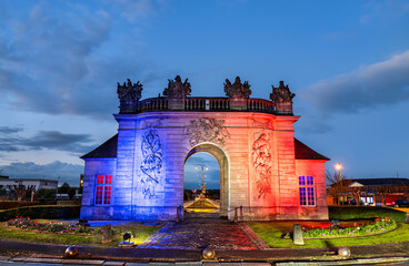 The historic Porte du Pont stone gateway illuminated with the colors of the French flag at dusk in Vitry-le-Francois, France.