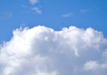 Fototapeta premium Fluffy white cumulus clouds on a clear bright blue sky background, beautiful sunny day.