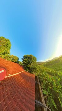 Vertical video. Early Evening Light over Jungle Hills and Rooftops with Clear Blue Sky Timelapse of Sunset in Tropical Forest
