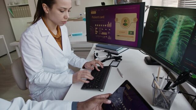 Handheld shot of two diverse young doctors in white coats using artificial intelligence assistance while examining patients cards and x ray on digital devices