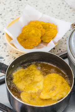 Golden tostones frying in hot oil on stovetop