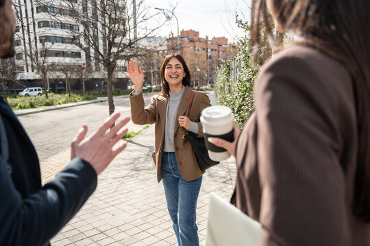 Business colleagues greeting on city street with coffee