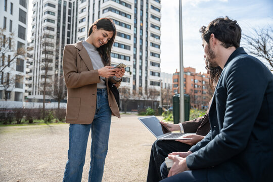 Young professionals networking outdoors with laptop and phone