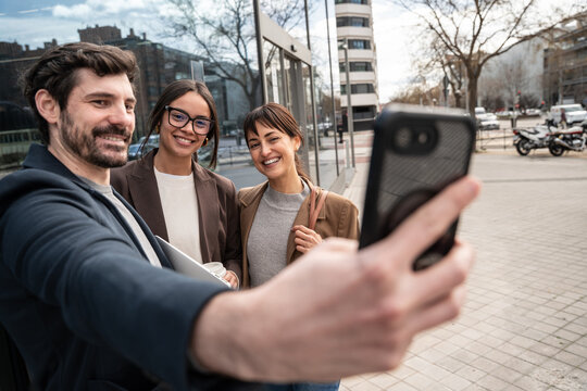 Friends taking smartphone selfie on city street outdoors