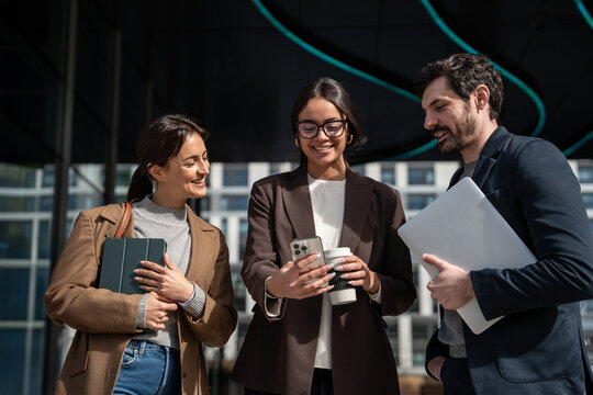 Business team collaborating outdoors with laptop and smartphone