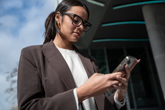 Businesswoman using smartphone outside office building