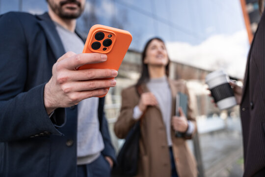 Business people using smartphone outside modern office building