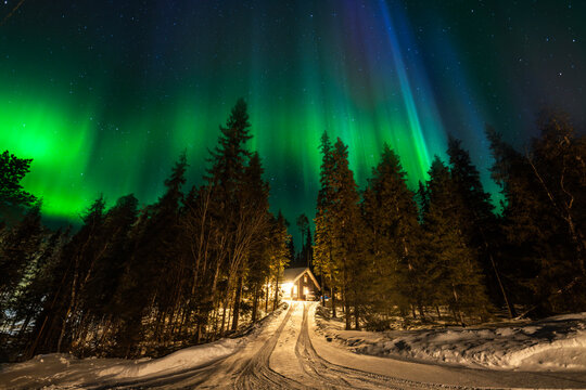 Northern lights over snowy forest cabin in Finland