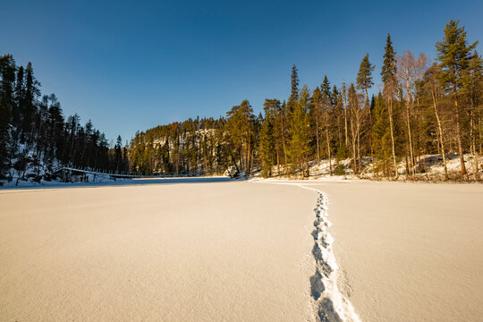 Winter footprints across a frozen lake in Finland forest