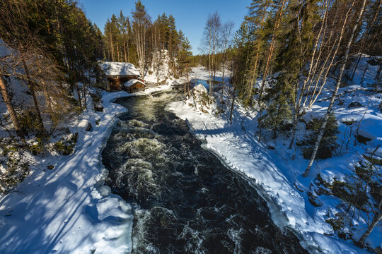 Winter river rapids through snowy forest in Finland