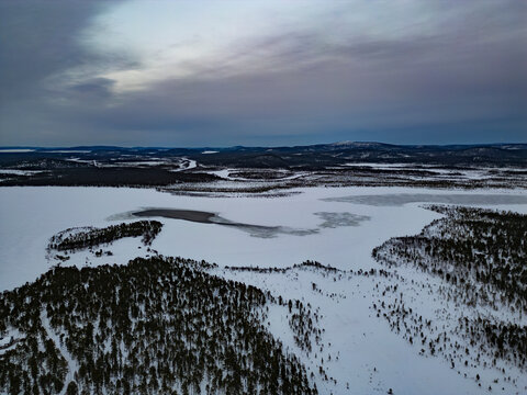 Aerial view of frozen lake and snowy forest in Finland